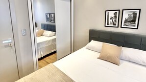 A modern bedroom with a large bed, a wardrobe, and two framed pictures on the wall.