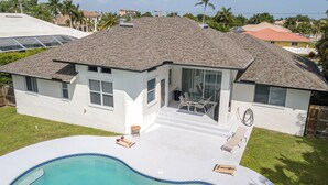 Una casa de dos pisos con piscina, un patio cubierto y vistas a otras viviendas.