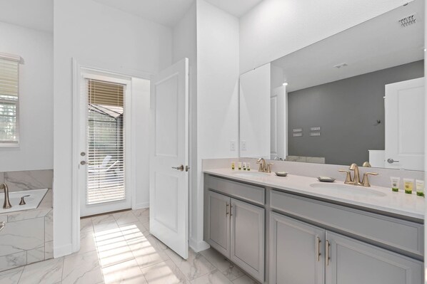 Un baño moderno con un espejo grande, un lavabo con grifo dorado y una zona de ducha con puerta de cristal.
