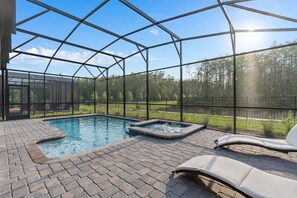 Un área de piscina exterior techada con un jacuzzi, sillones de descanso y vistas a un bosque.