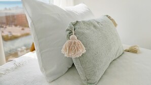 A bed with two pillows, one plain and one with a tassel, in a room with a view of the beach. - Global Vacacional: Apartment with sea views, Canet d'en Berenguer (Canet d´en berenguer)