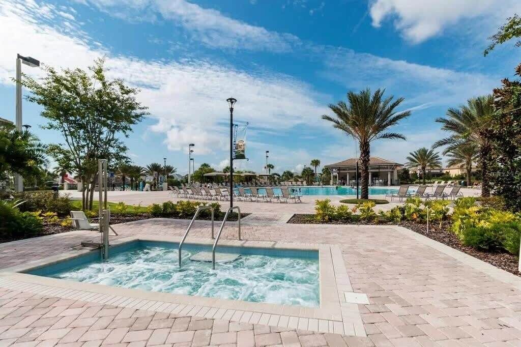 Un espace piscine doté d’un jacuzzi, de chaises longues et de palmiers.