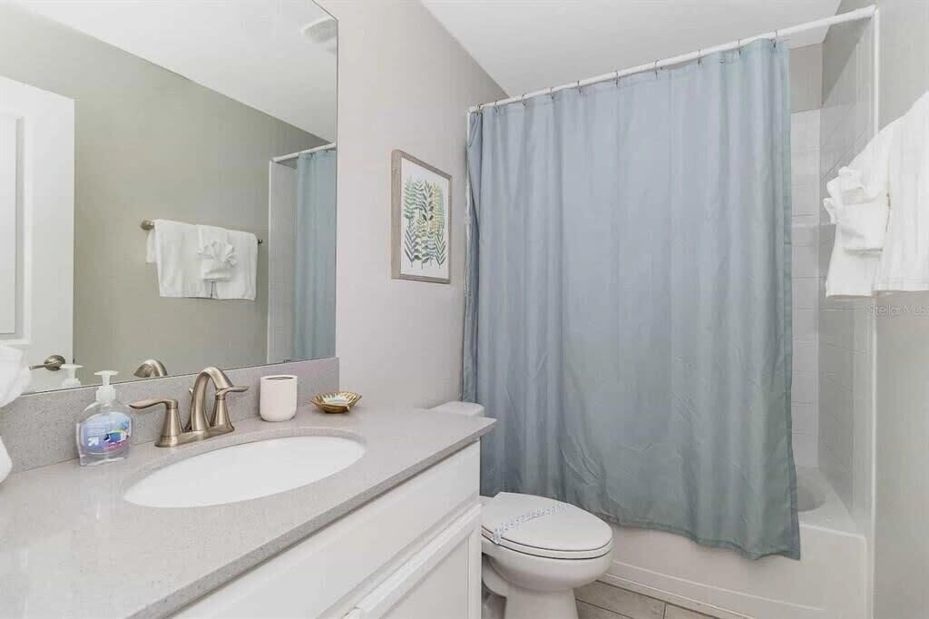 Een badkamer met een witte wastafel, een spiegel, een toilet en een douchegordijn.
