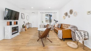 Ett modernt vardagsrum med en öppen spis, en tv, en soffa och en matplats.