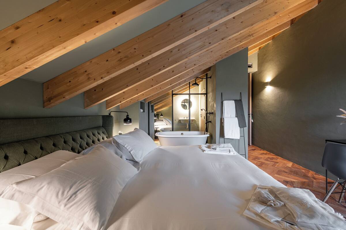 Ein Schlafzimmer mit einem großen Bett, einer Badewanne und einer Holzbalkendecke.