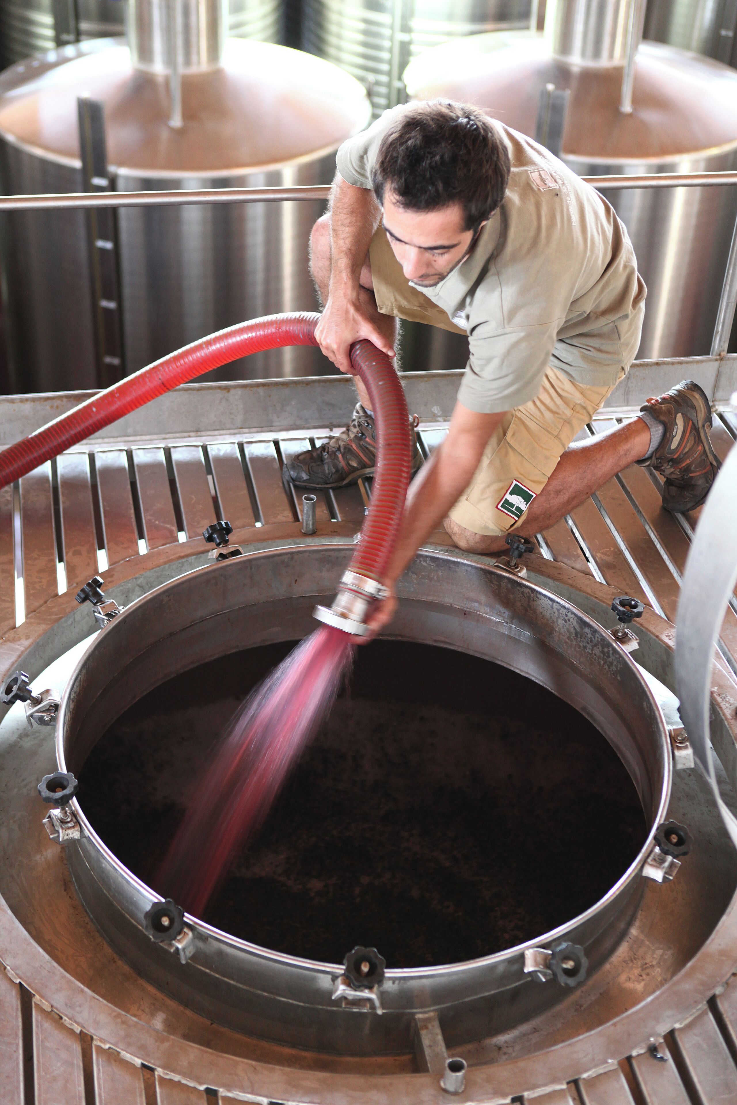 Una persona operando una máquina industrial grande con una manguera roja.