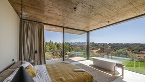 Un dormitorio moderno con una cama grande, una bañera y vistas al campo.