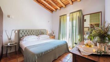 A bedroom with a bed, bedside table, lamp, and a mirror.
