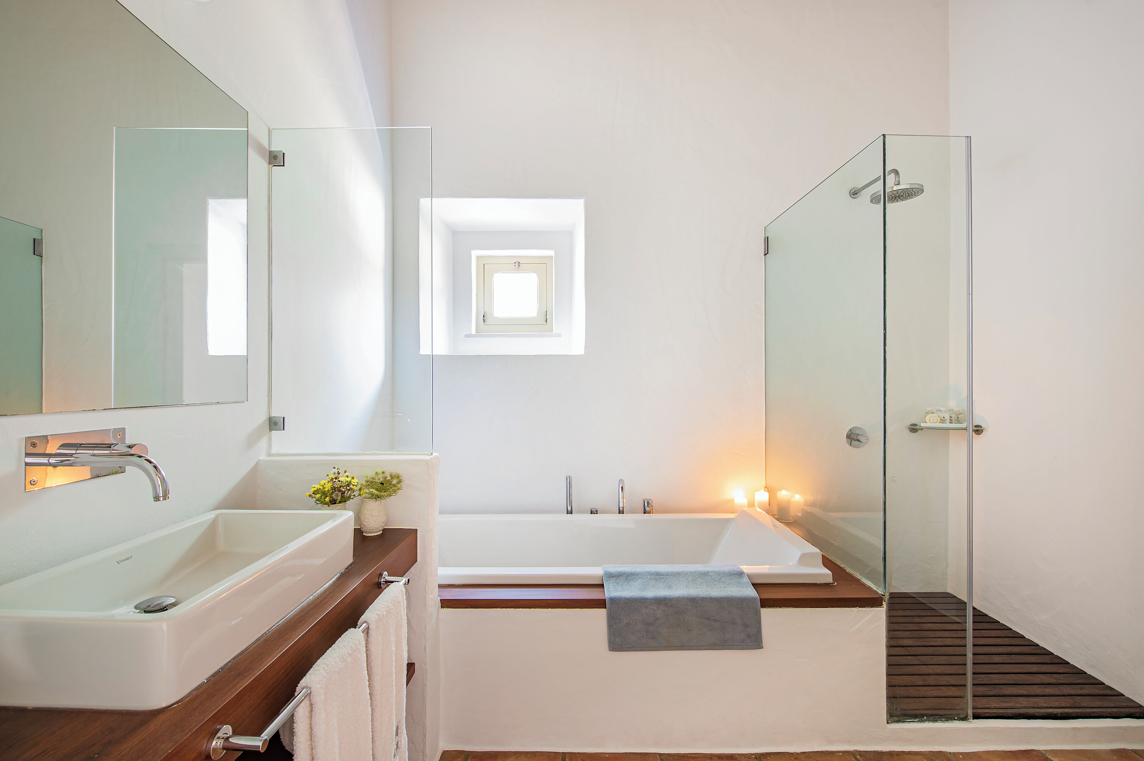 Un baño moderno con un espejo grande, una bañera y un box de ducha de vidrio.