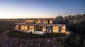 Una casa moderna de varios pisos con un amplio espacio exterior, que incluye una piscina y mobiliario.