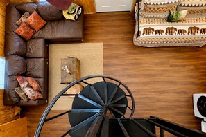A spacious living area with a brown leather sofa, a patterned rug, and a wooden coffee table. - Romantic Cabin: Hot Tub, Fire Pit, Indoor & Outdoor Living, EV Charger (Martin)