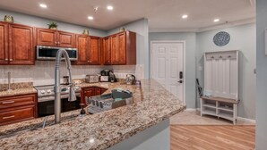 Una cocina moderna con encimeras de granito, armarios de madera y electrodomésticos de acero inoxidable, incluyendo un lavavajillas integrado.