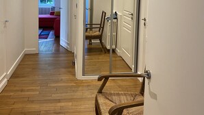 A hallway with wooden flooring, a chair, and a door leading to another room.