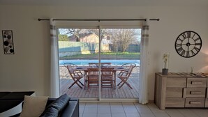 En stue med en skydedør til en terrasse med et træbord og stole.