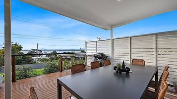 Enjoy al fresco dining with a view of the water and distant hills from this outdoor dining area, featuring a barbecue grill and comfortable seating for six.