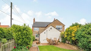 A house with a paved driveway, a lawn, and a wooden fence. - 2 bedroom accommodation in Snitterby (Snitterby)