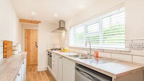 A modern kitchen with white cabinetry, a stainless steel sink, and a window with blinds. - 2 bedroom accommodation in Snitterby (Snitterby)