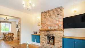 A room with a brick fireplace, wooden dining table, and blue cabinets. - 2 bedroom accommodation in Snitterby (Snitterby)