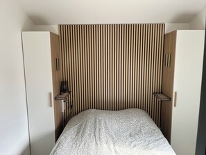 Une chambre à coucher avec un lit, une tête de lit en lattes de bois et deux tables de chevet.