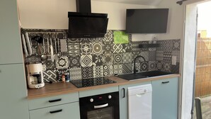 A compact kitchen with a built-in oven, dishwasher, and a black range hood. - Landes house Dax (Dax)