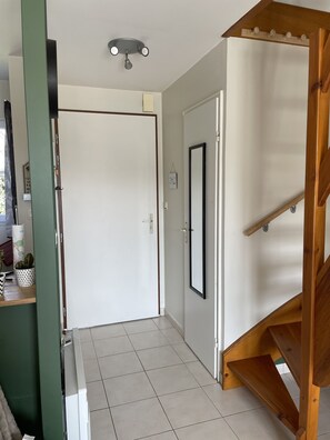 A hallway with a wooden staircase, a white door, and a ceiling light fixture.
