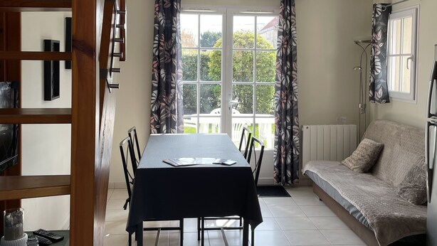 Et spiseområde med et bord, stole, en sofa og en trappe.