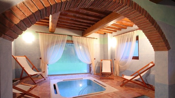 A spa room with a hot tub, two wooden chairs, and a window with sheer curtains. - Villa Consolata, Large country villa with pool (Reggello)