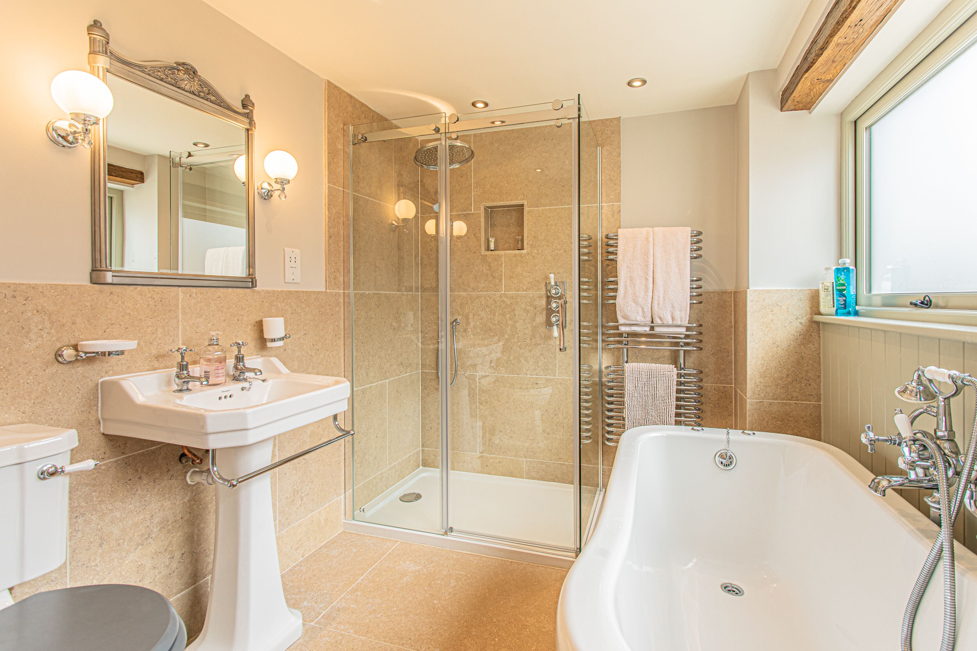 Une salle de bain moderne dotée d’une douche à parois de verre, d’une baignoire sur pieds et d’un meuble-lavabo avec un évier et un miroir.