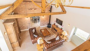 Ein Loft-Wohnzimmer mit freiliegenden Holzbalken, einer Ziegelwand, einem Kamin und einem großen Fenster.