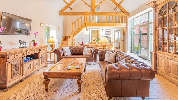 Ein geräumiges Wohnzimmer mit einer großen Ledersofa, einem Holztisch und einer Treppe, die in einen oberen Bereich führt.