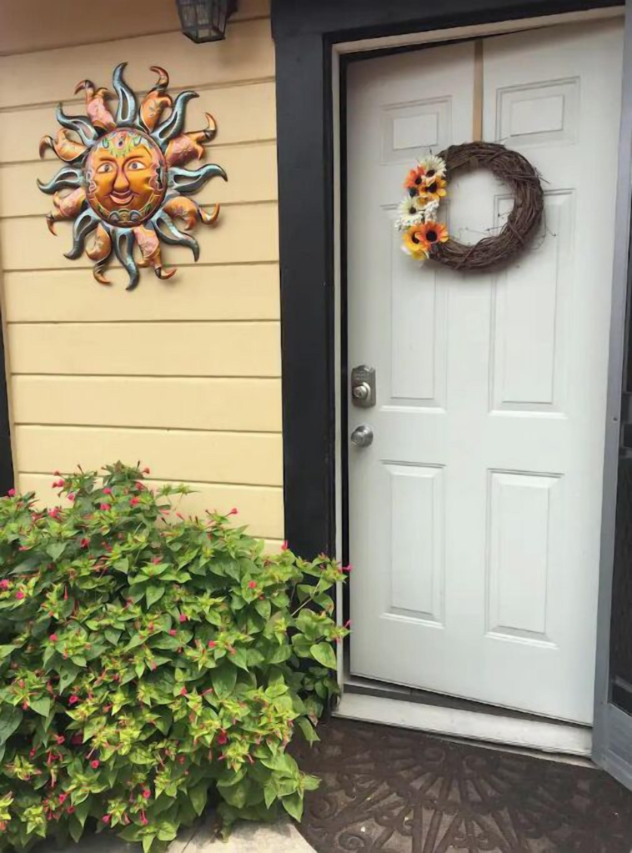 A white door with a wreath and a sun-shaped decoration on the wall.