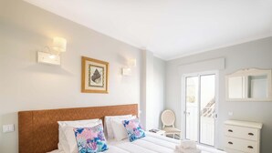 Une chambre d’hôtel comprenant un lit, une chaise, une commode et une porte donnant sur un balcon.