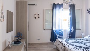 A bedroom with a bed, a desk, and a ship model.