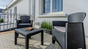 A balcony with wicker furniture, a table, and a potted plant. - The Villa Reina (Le Croisic)