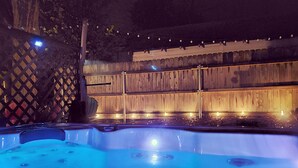 A hot tub with a wooden fence and string lights in the background. - LAKEVIEW Hot Tub Retreat Near Wineries! (Silver Creek)