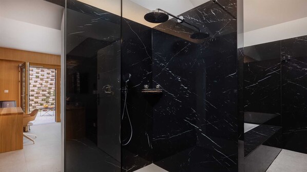 Ein modernes Badezimmer mit einer Duschkabine aus Glas, einer Holzbank und einem durch die Scheibe einsehbarer Küchenbereich.