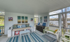 A covered porch with a sofa, a bench, and a dining table.