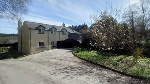 A two-story house with a driveway leading to a gated entrance.