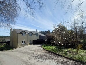 A two-story house with a driveway leading to a gated entrance.