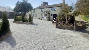 A two-story house with a gravel driveway and a wooden fence.