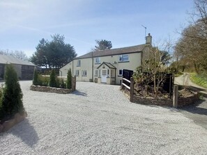 A two-story house with a gravel driveway and a wooden fence.