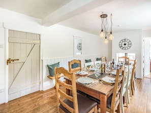 Un coin repas avec une table en bois dressée pour le repas, entourée de chaises en bois dotées de coussins.