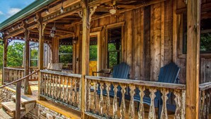 A wooden porch with a stone foundation, wooden railings, and Adirondack chairs. - Old Fellow's Farmhouse (Kerrville)