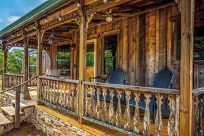 A wooden cabin with a porch, stone steps, and Adirondack chairs. - Old Fellows Farmhouse | 2BR with Country Views (Kerrville)