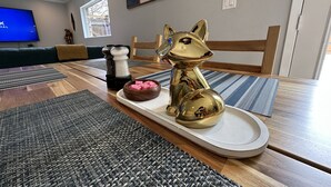 A dining area with a wooden table, woven placemats, a decorative dog figurine, salt and pepper shakers, and a bowl of pink candies. - 3 KING BEDS - 3 QUEEN - 4 TWINS - 5 BED ROOMS (Houston)