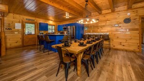 A wooden cabin with a large dining table, bar area, and kitchen.