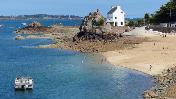 A coastal scene with a rocky outcrop, a white house, and a sandy beach. - Le Clos des Pommiers (PAIMPOL)