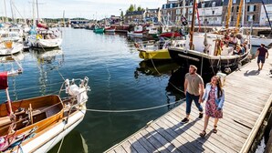 A marina with boats docked, a wooden pier, and buildings in the background. - Le Clos des Pommiers (PAIMPOL)