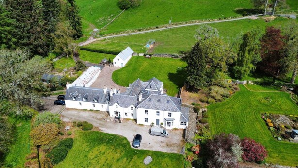 A large, white, two-story building with a steeply pitched roof, surrounded by well-maintained lawns and trees. - The Gardeners Cottage -  Retreat Group (Pitlochry)