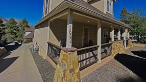 A two-story house with a covered porch and stone pillars. - Hillside Home: Amazing Views w/ Big Deck 5 Min. From Downtown + Trailheads! (Flagstaff)